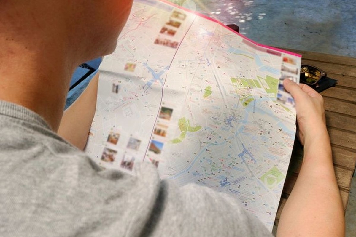 A traveler reading a folded city map at an outdoor table