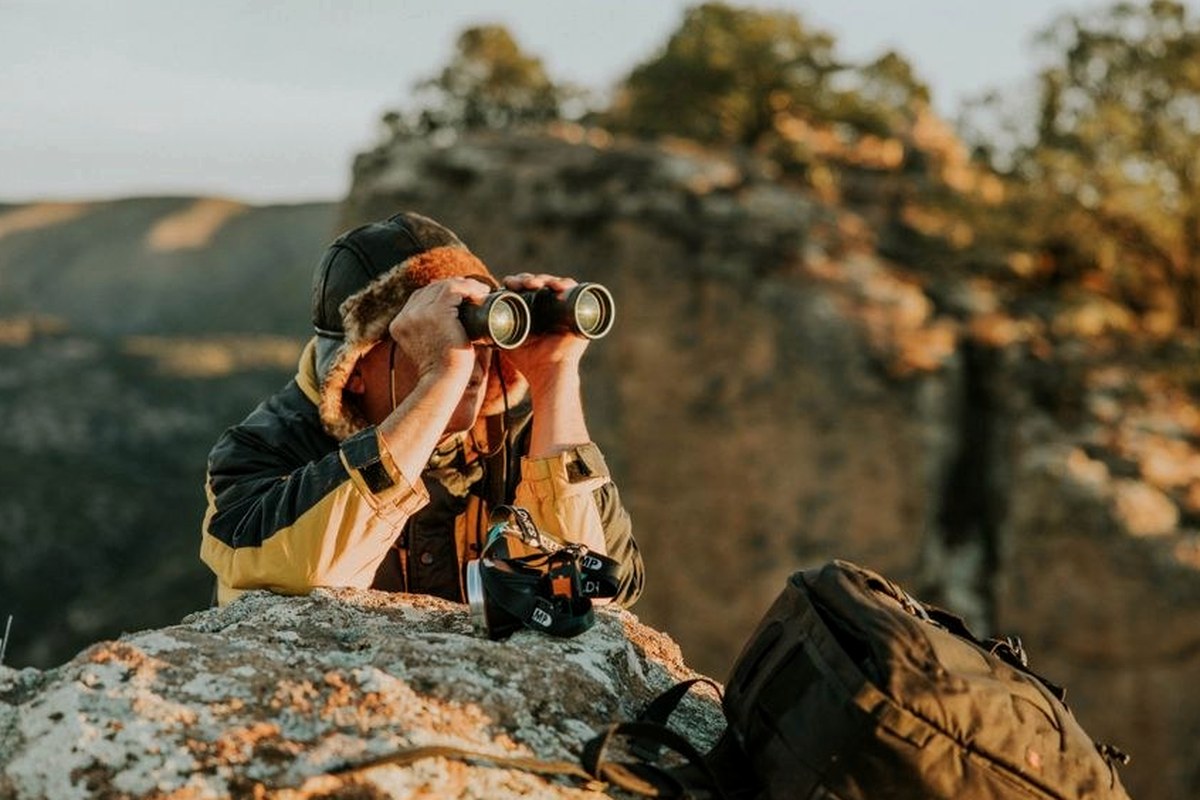A photographer pausing on a rocky overlook with a camera
